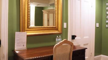 A room with a wooden desk, a chair, a large mirror, and a door.