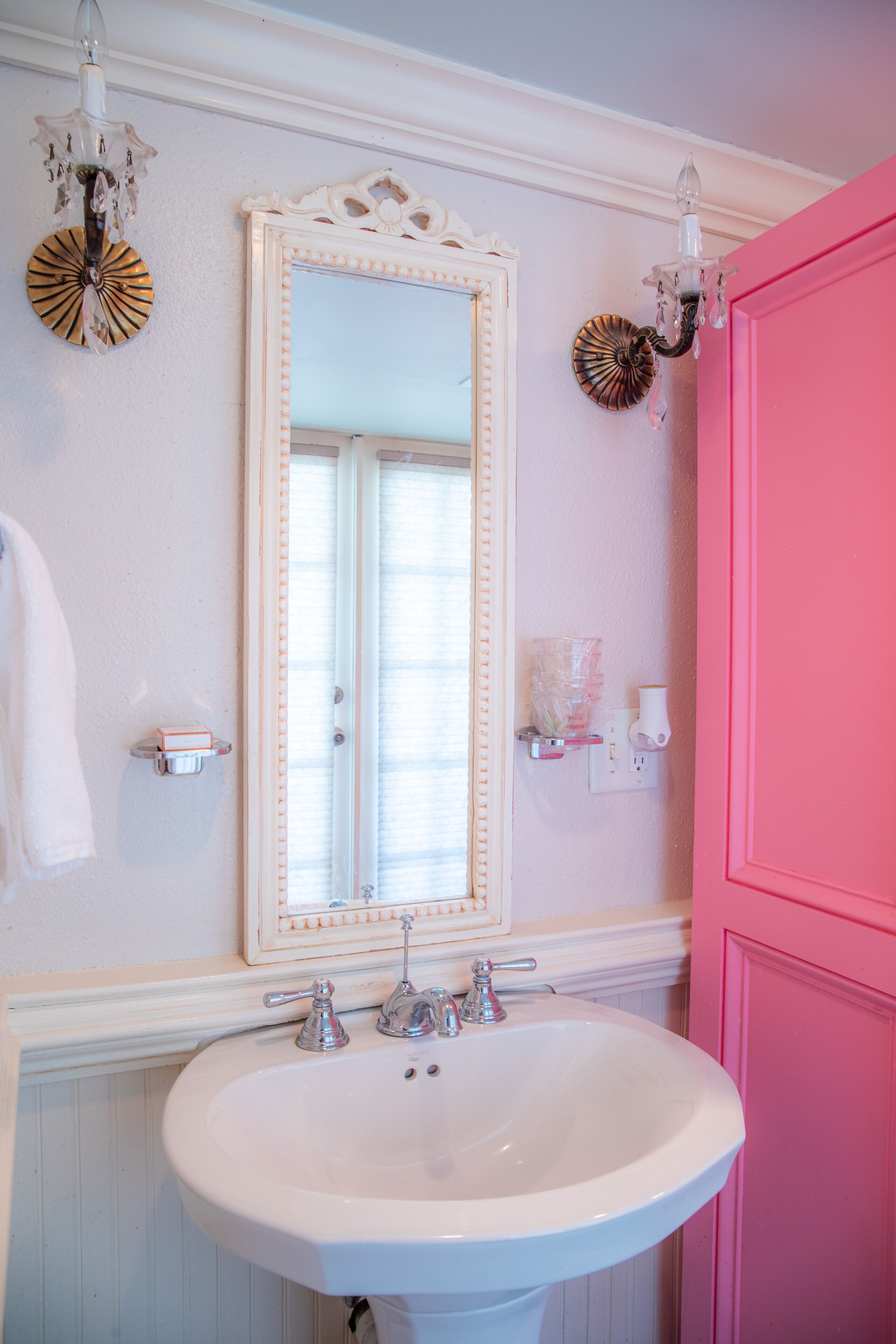Een badkamer met een wit wastafel, een spiegel en een roze deur.