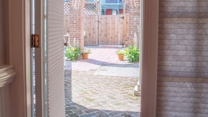 A doorway leading to a brick patio with a wooden fence and potted plants.