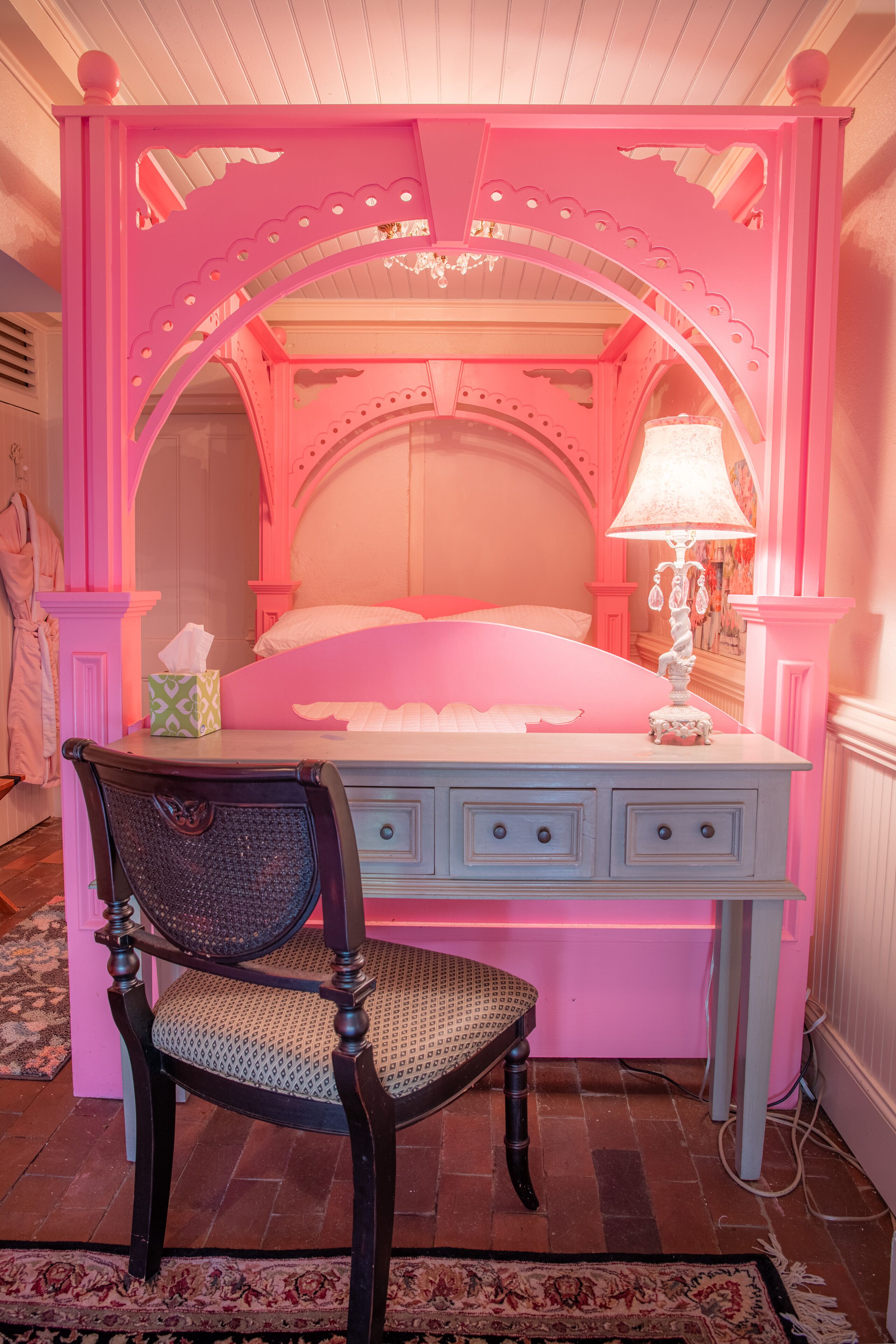 A pink-themed bedroom with a bed, a dresser, and a chair.