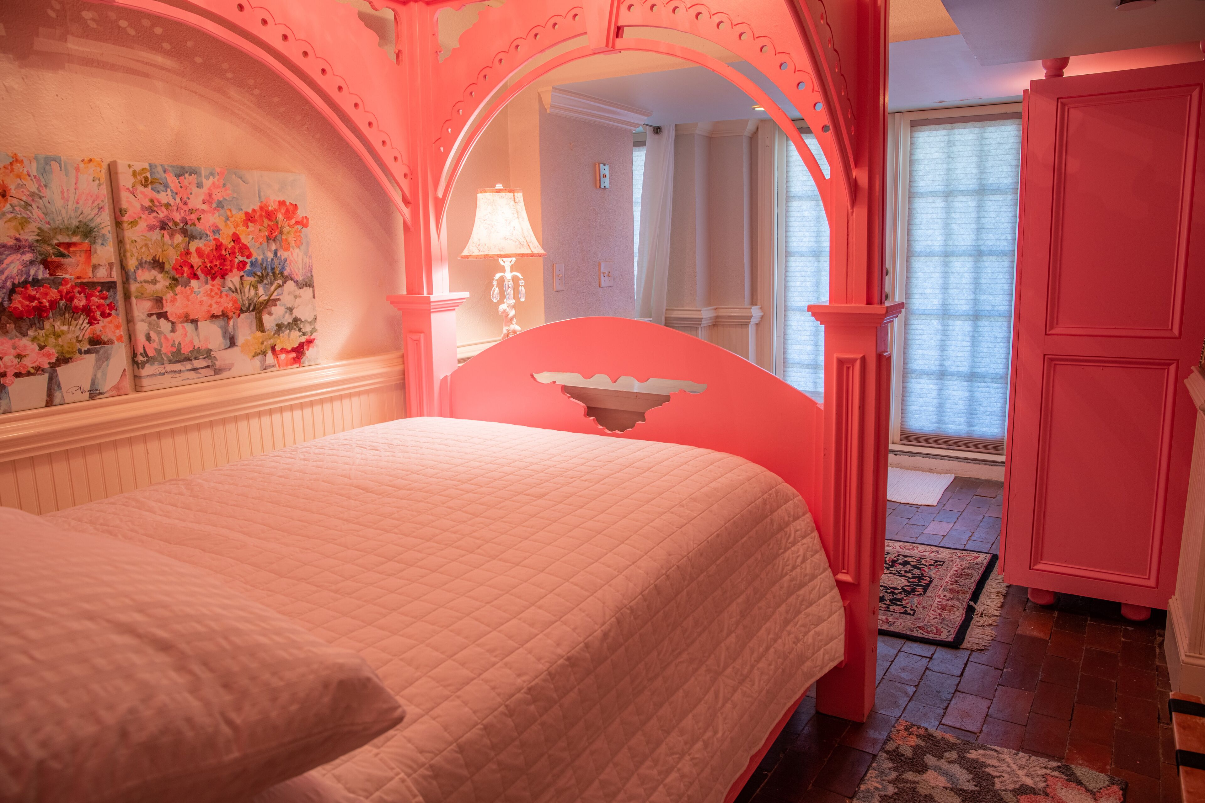 A pink-themed bedroom with a bed, a mirror, and a door.