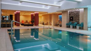 Un área interior de piscina moderna con una piscina limpia, zonas de estar y un mostrador de recepción.
