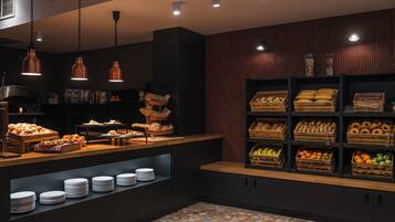 Un mostrador de panadería con diversos productos horneados y una exhibición de frutas y verduras.