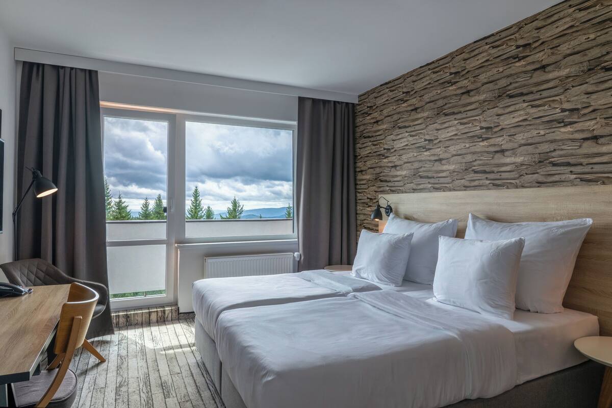 Una habitación de hotel con cama, escritorio y vistas al exterior.