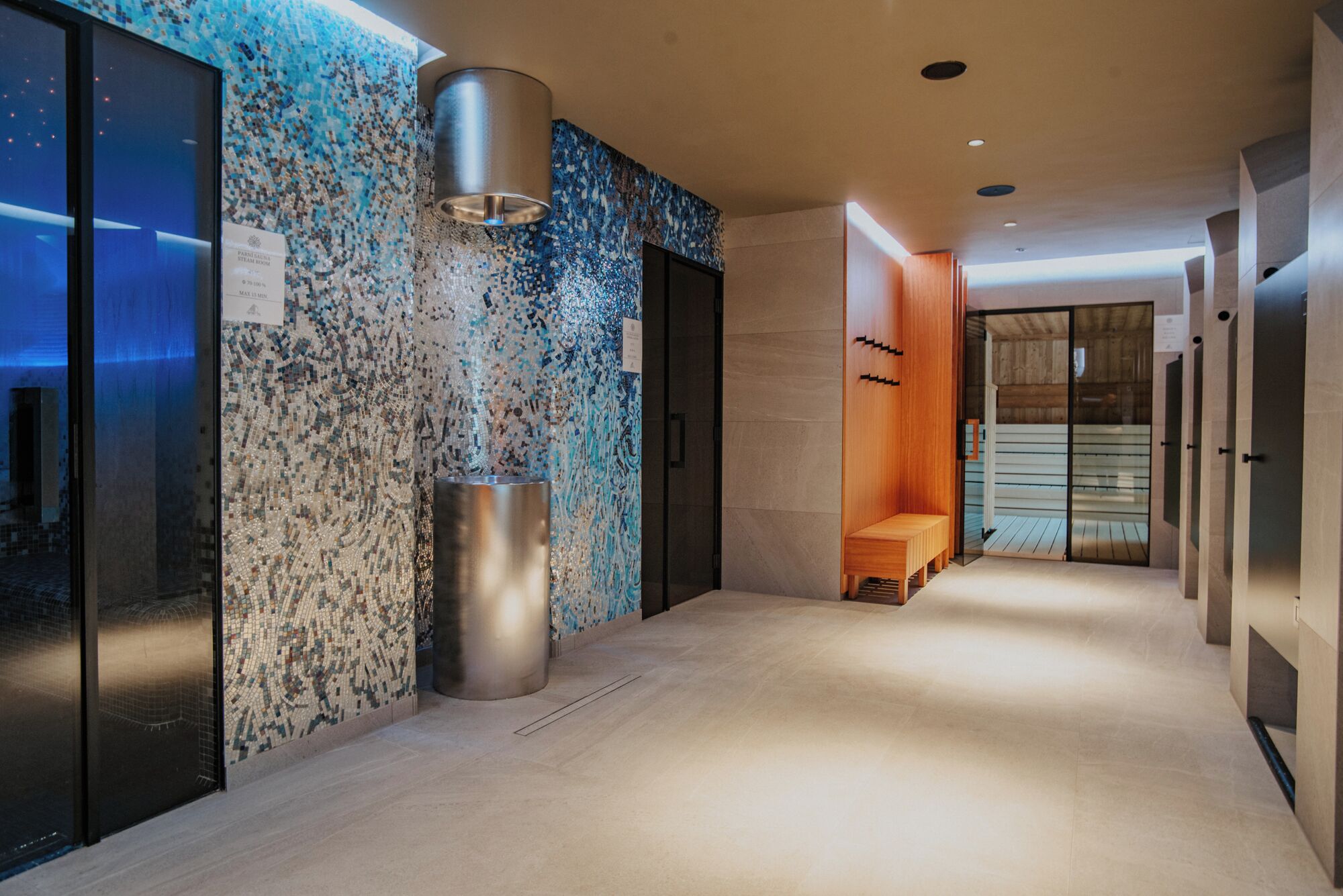 Ein moderner Flur mit einer Mosaikwand, einer zylindrischen Säule und einer hölzernen Bank.