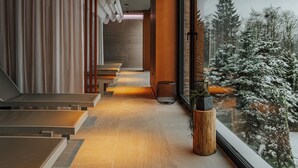 Un interior moderno con una escalera, un ventanal con vistas nevadas y una planta en maceta.