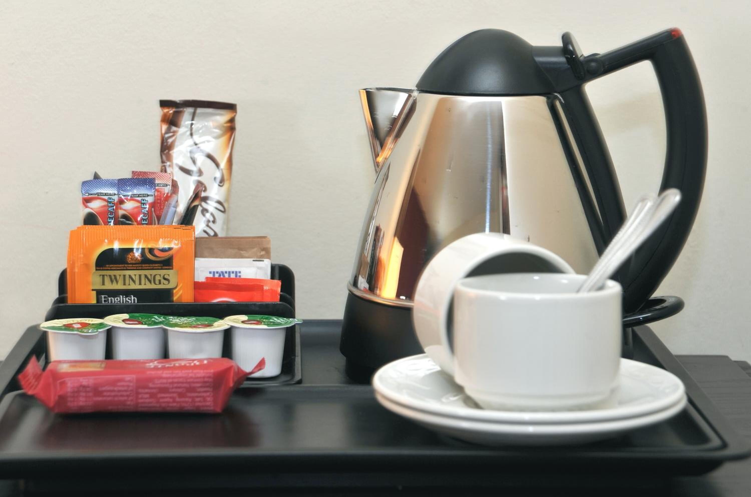 Ein Tablett mit Twinings English Tee, Twinings Teebeuteln, Twinings Teecreme sowie einer weißen Tasse und einem Untertasse.