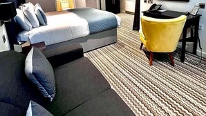 Una habitación de hotel moderna con cama, sofá, escritorio y televisor.