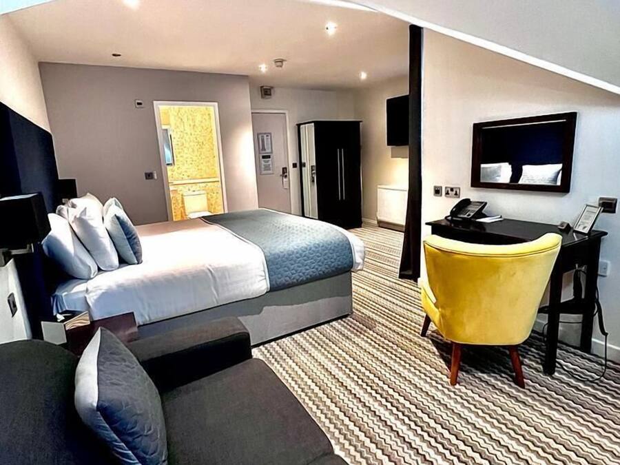 Una habitación de hotel moderna con cama, sofá, escritorio y televisor.
