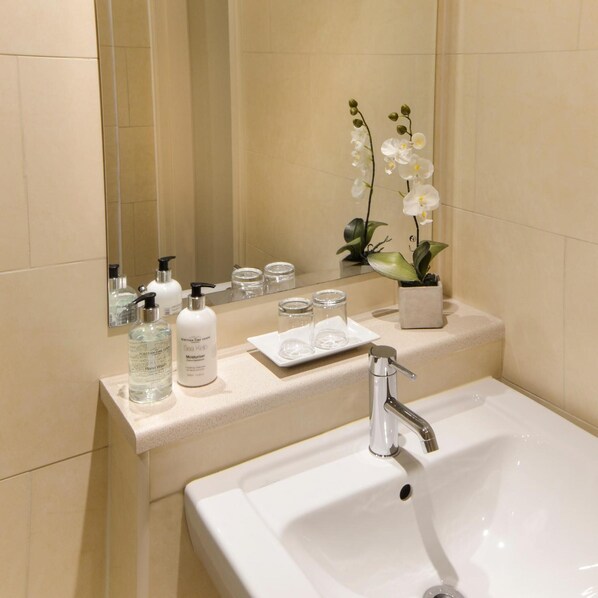 A bathroom with a white sink, a mirror, and toiletries on the counter.
