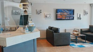 Una sala de estar moderna con un sofá, una mesa de centro y un televisor montado en la pared sobre una chimenea.