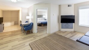 Habitación de hotel con cama, televisión, escritorio con silla, baño y una pequeña zona de estar.