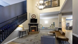 Amplia sala de estar con chimenea, una escalera y un rincón de descanso con sofás y una mesa de centro.