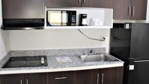 Una cocina equipada con microondas, cafetera, estufa, lavabo y refrigerador.