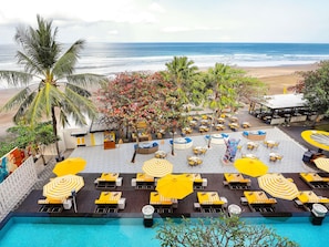 A poolside area with lounge chairs and umbrellas, a beach view, and a tropical setting. - Grand Seminyak Lifestyle Boutique Bali Resort by Accor (Seminyak)