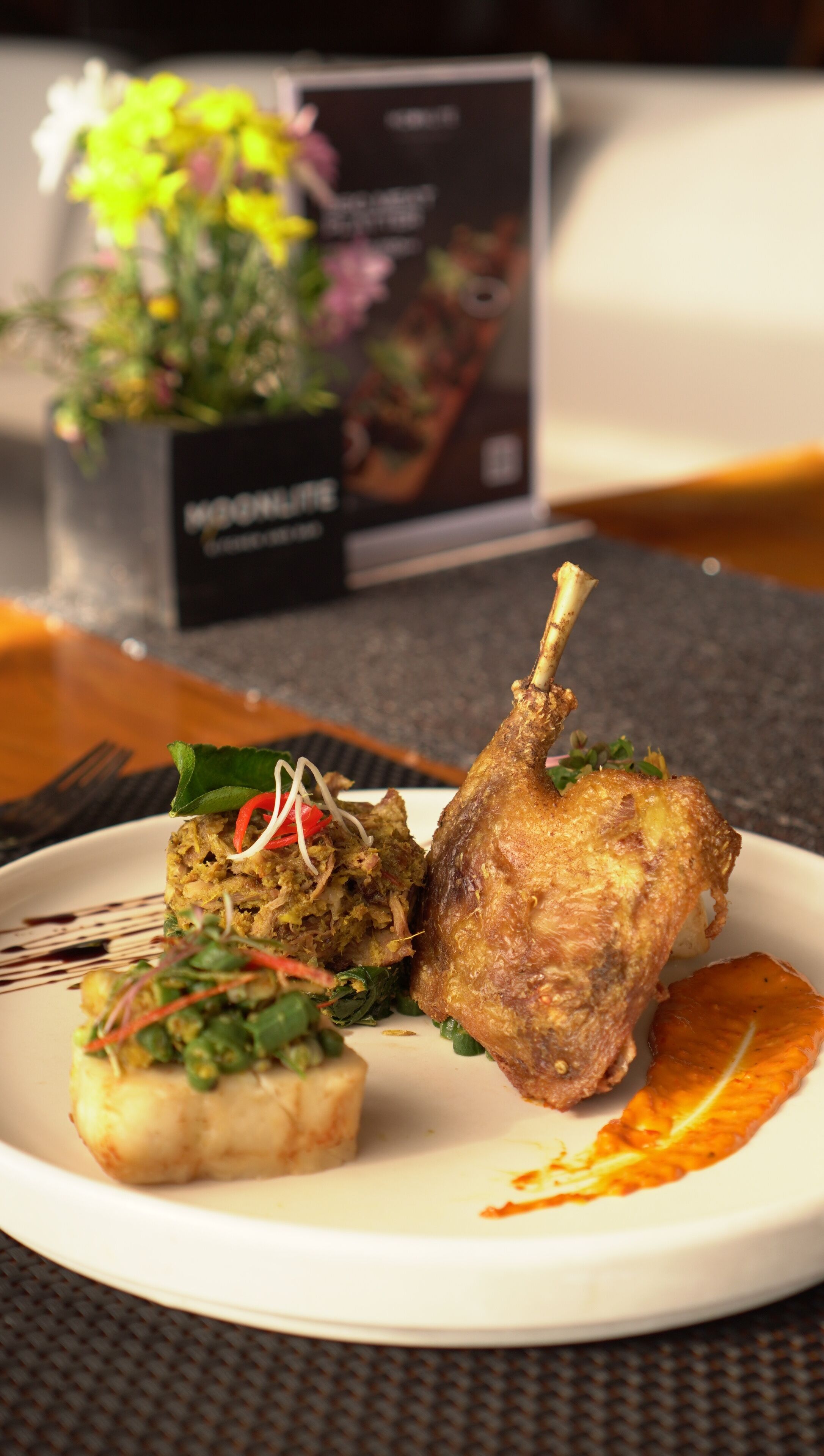 A plate with a roasted leg of lamb, a vegetable medley, and a piece of salmon.