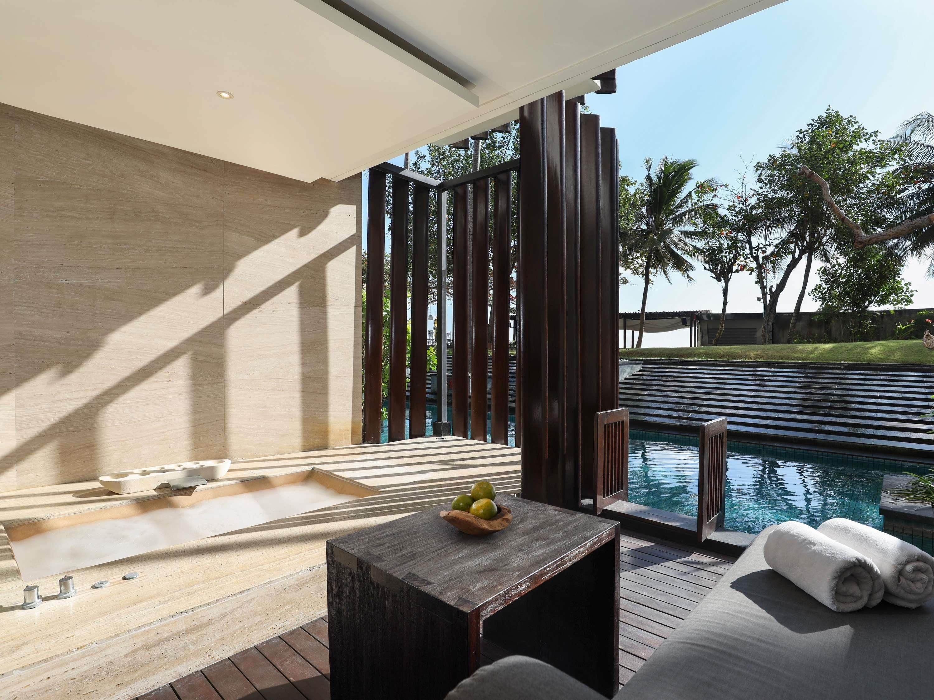 A modern outdoor pool area with a wooden deck, a seating area with a table, and a view of the pool.