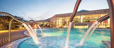 Een binnenzwembad, een buitenzwembad, ligstoelen bij het zwembad