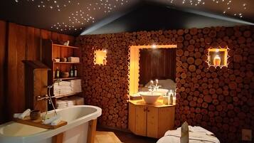 Relax in a spacious bathroom with a large bathtub, wooden side panel, and a wooden cabinet with sink and mirror.