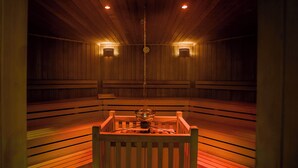A sauna with wooden benches and two wall-mounted lights. - Heide Spa Hotel & Resort (Bad Dueben)