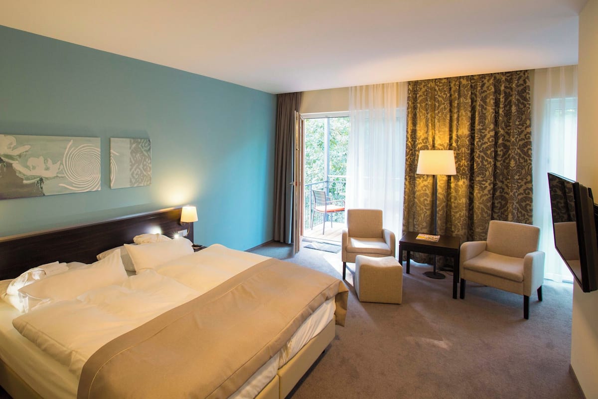 Una habitación de hotel con una cama grande, dos sillones, un escritorio y un televisor.