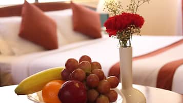 A fruit bowl with grapes, an apple, and a banana on a table in a hotel room.