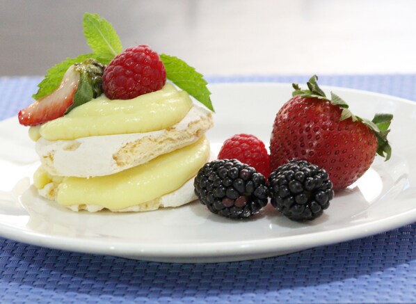 Un plato de postre con un pastel en capas, fresas y moras.