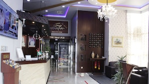 A reception area with a wooden counter, a chandelier, and a sign for 'The Trap Pub' on the mezzanine floor.