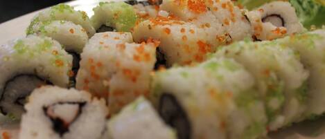 Un piatto di involtini di sushi con diversi condimenti.