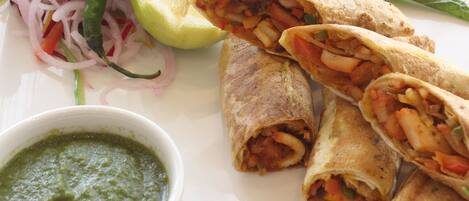 Lautasella on tortilloja, sitruuna ja kulho kastiketta.