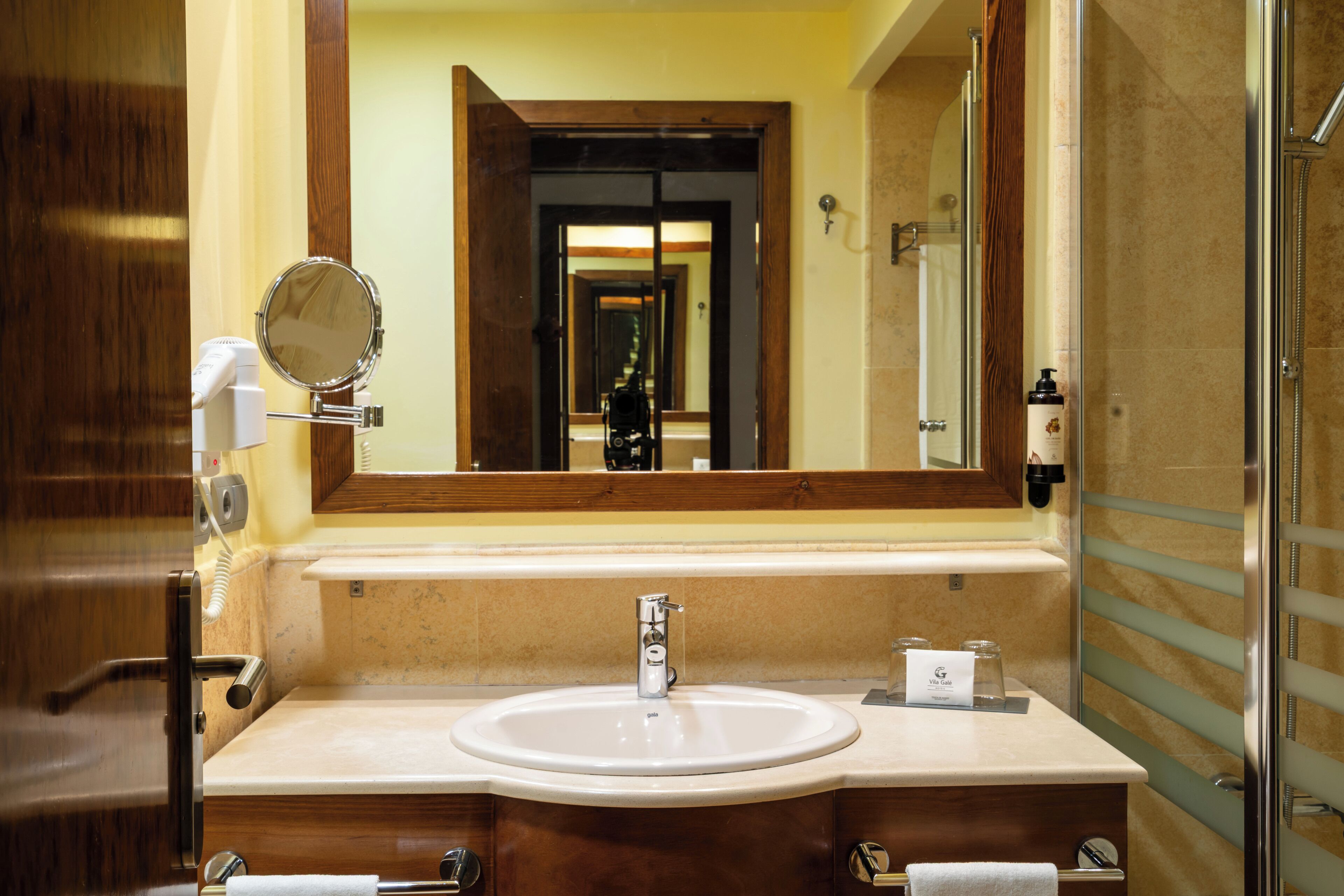 A bathroom with a round mirror, a sink, and a shower area.