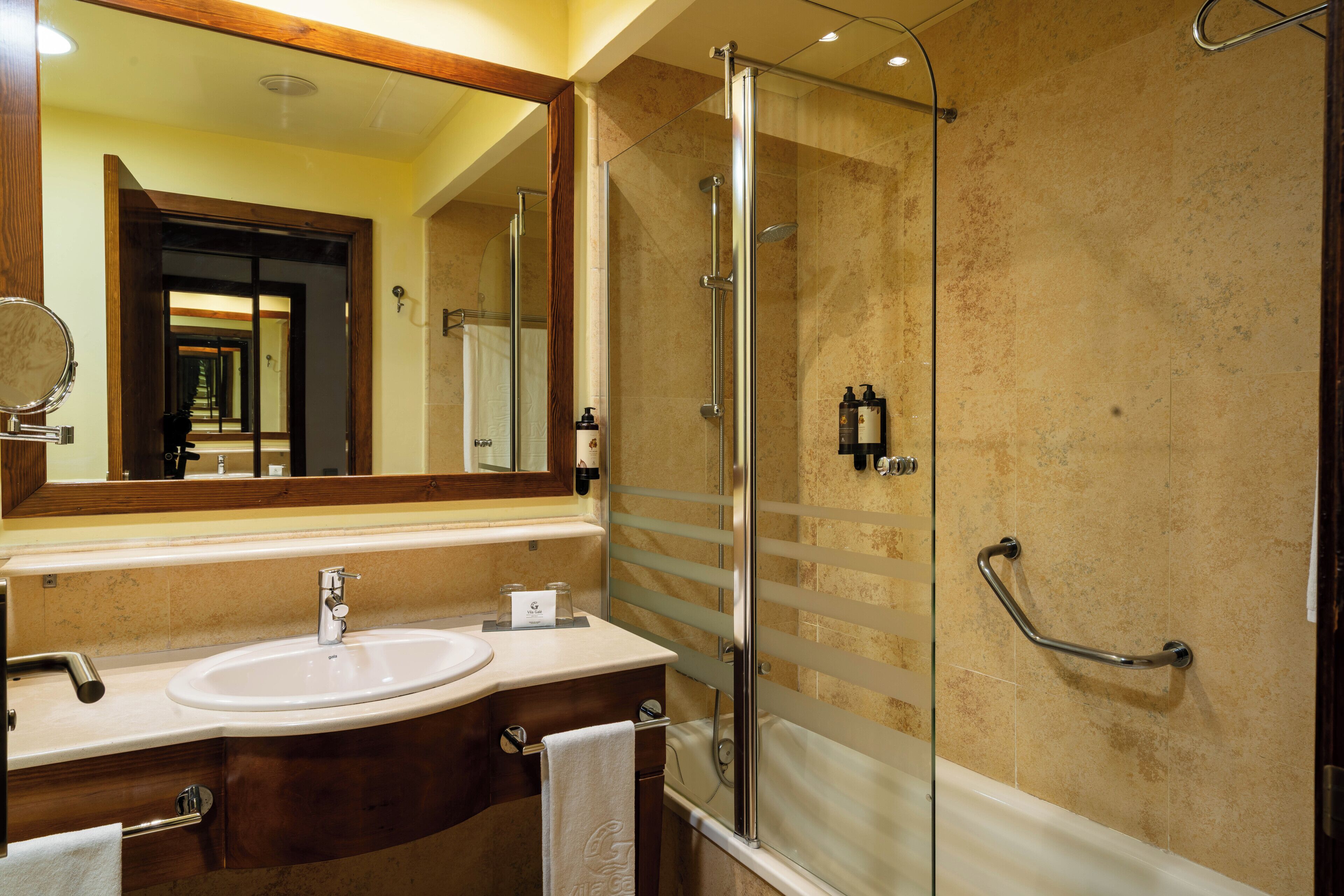 A bathroom with a glass-enclosed shower, a sink with a mirror, and a towel rack.