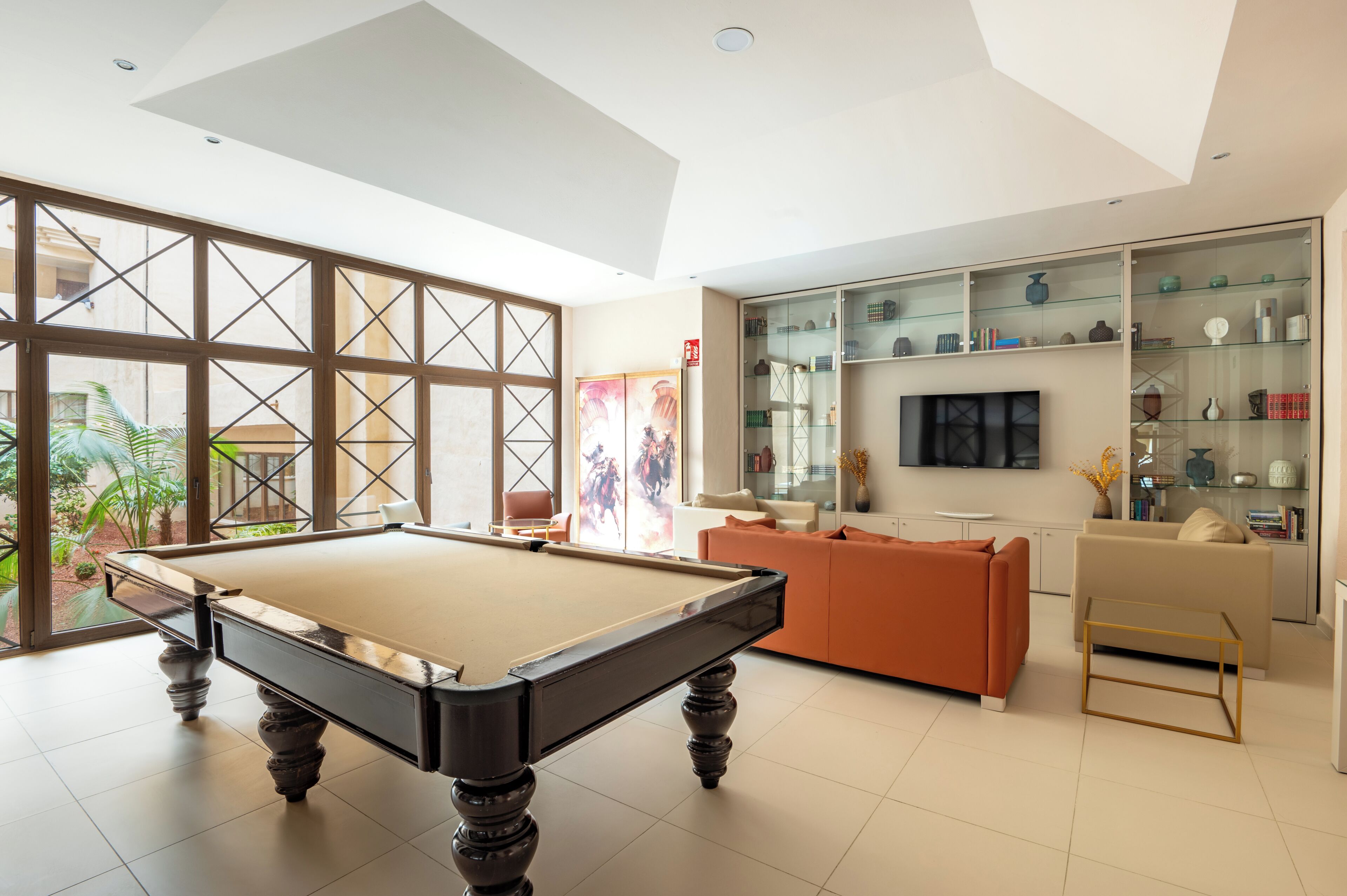 A modern living room with a pool table, a sofa, and a TV.