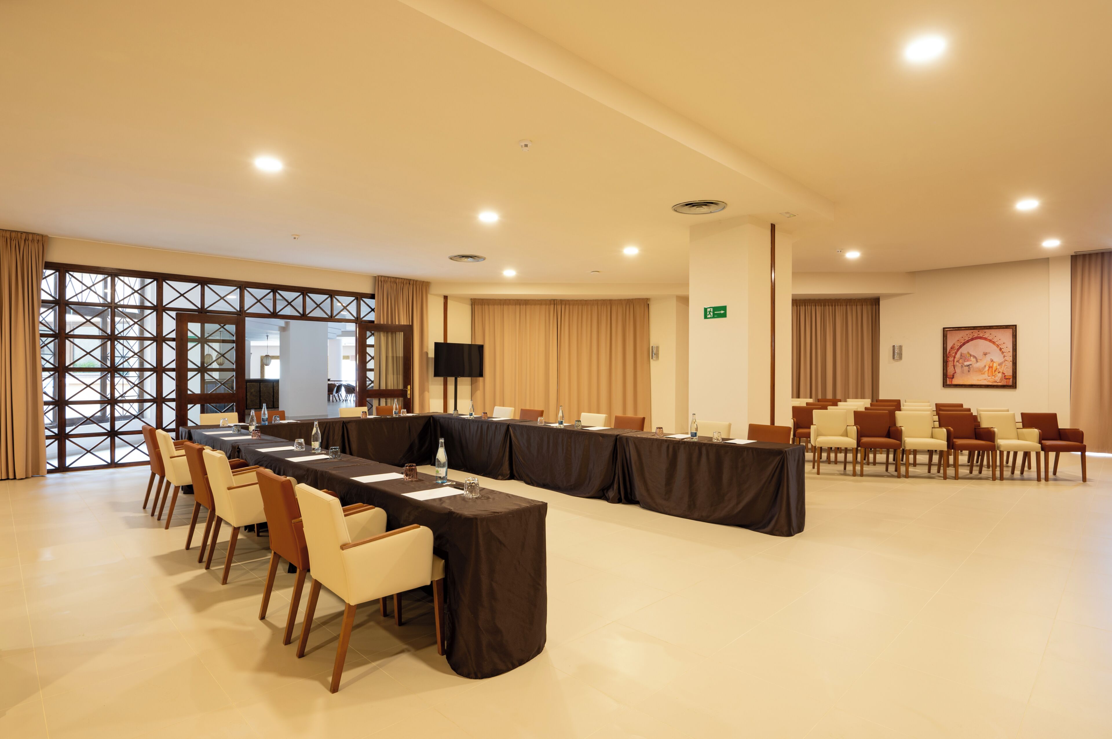 A conference room with a long table, chairs, and a television screen.