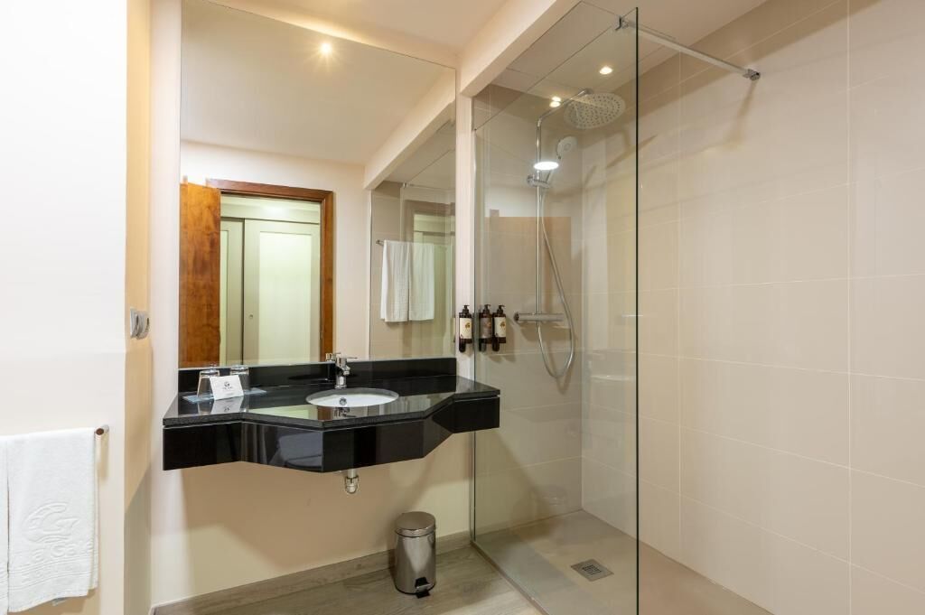 A modern bathroom with a glass-enclosed shower, a black sink vanity, and a mirror.