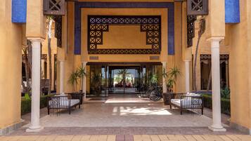 A hotel entrance with a covered walkway, columns, and outdoor seating.