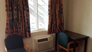 Una habitación con ventana, dos sillas, una mesa y un equipo de aire acondicionado.