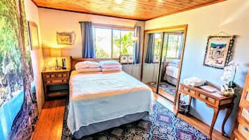 Un dormitorio con cama, mesita de noche, espejo y vistas al exterior.