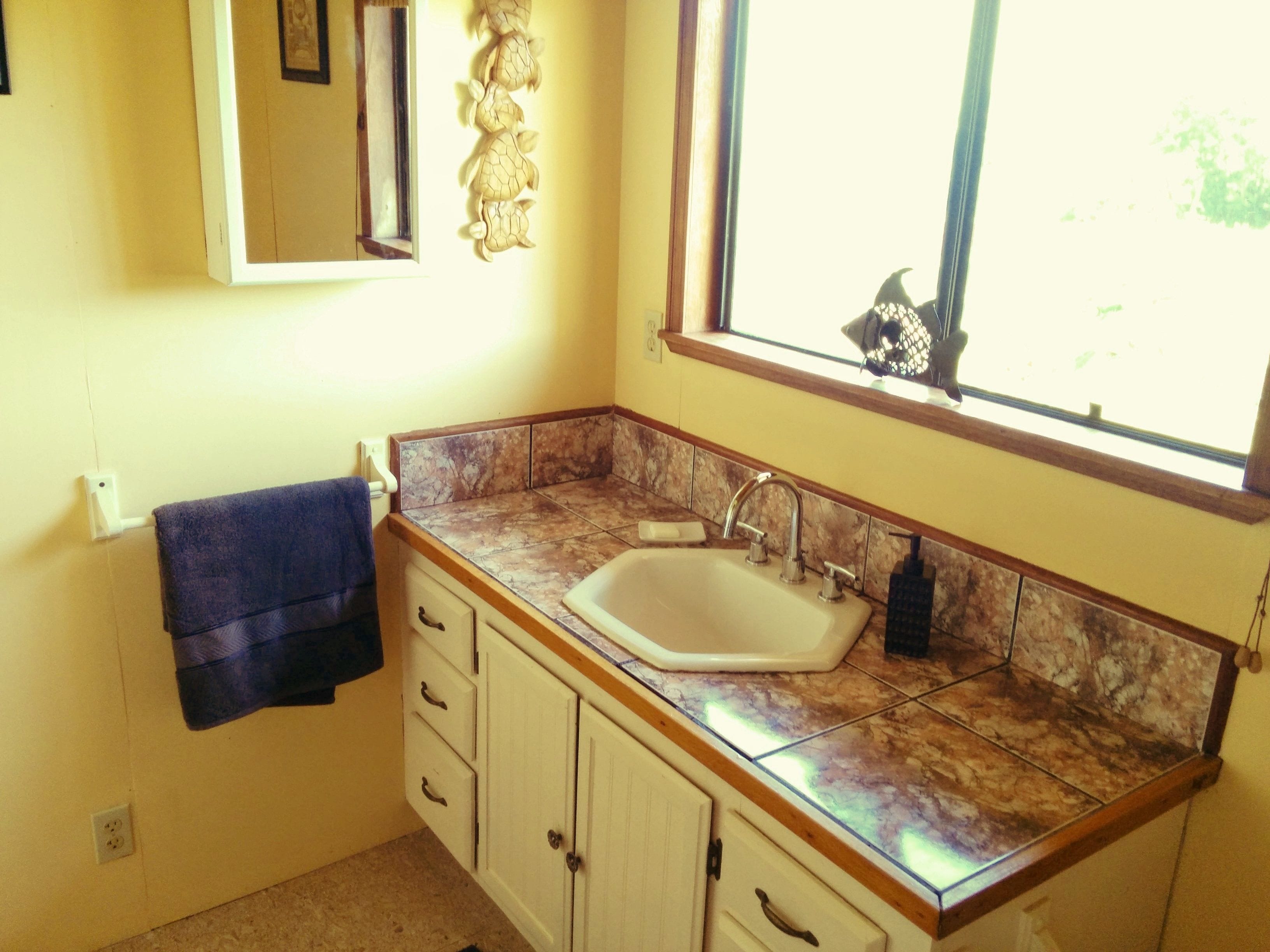 Un baño con lavamanos, espejo y ventana.