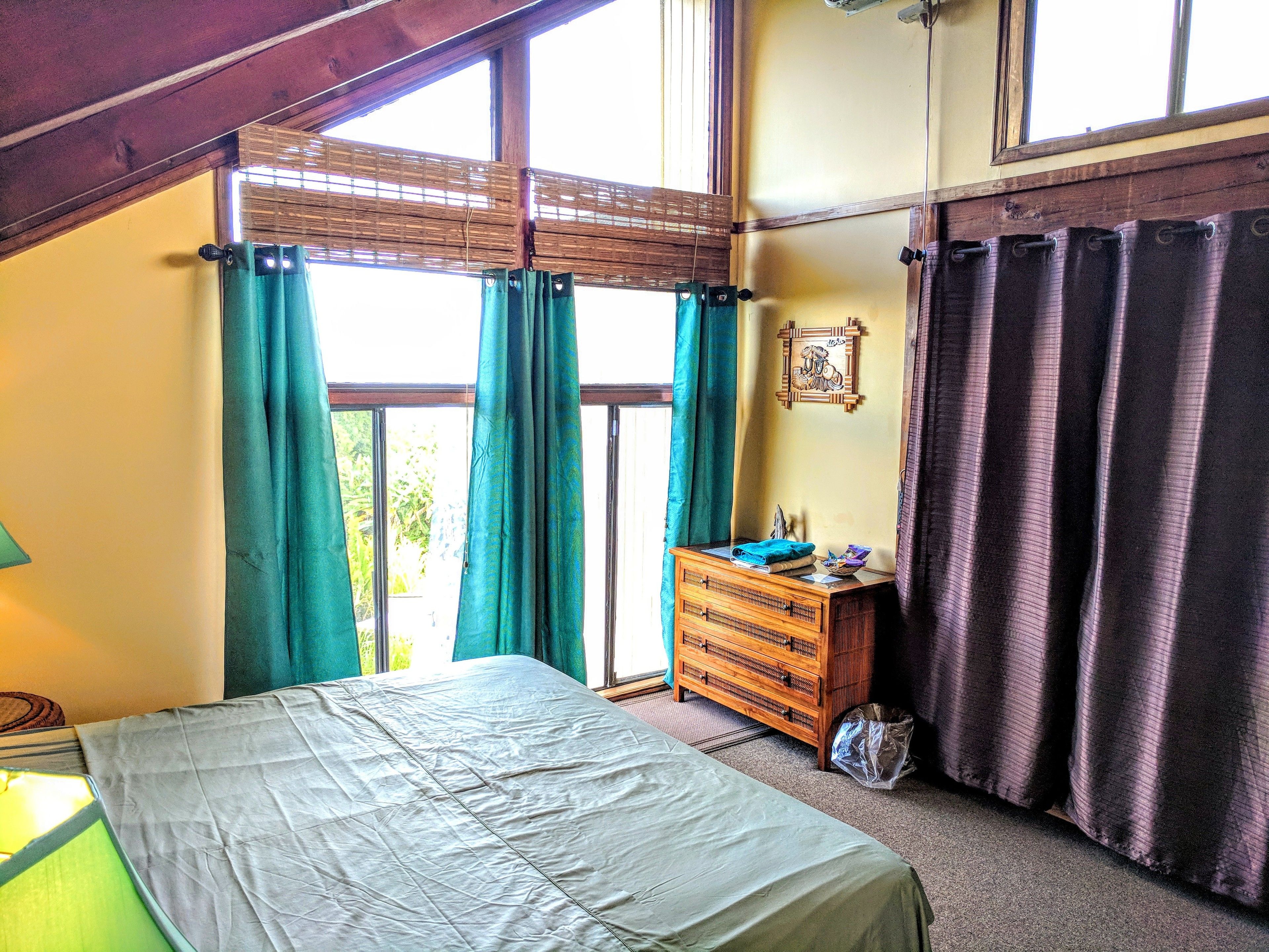 A bedroom with a bed, a dresser, and a window with curtains.