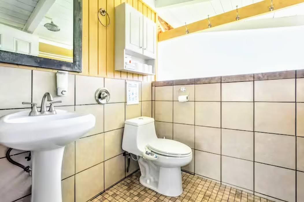 A bathroom with a white sink, toilet, and tiled walls.