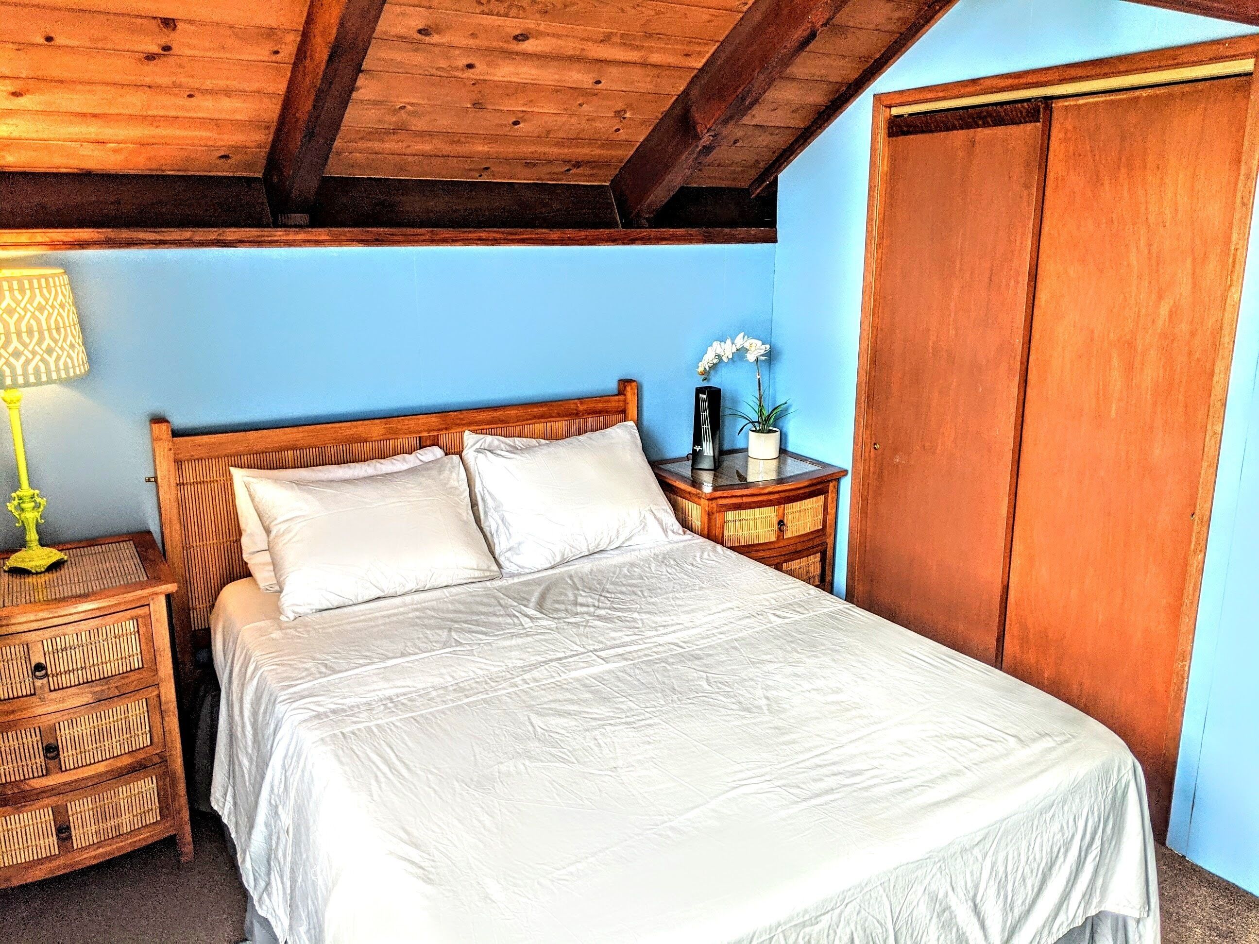A bedroom with a wooden bed, a nightstand with a lamp, and a wardrobe.