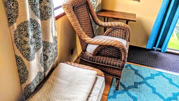 A wicker chair with a cushion, a small wooden table, and a patterned rug.
