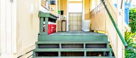 A covered porch with green steps leading to a door.