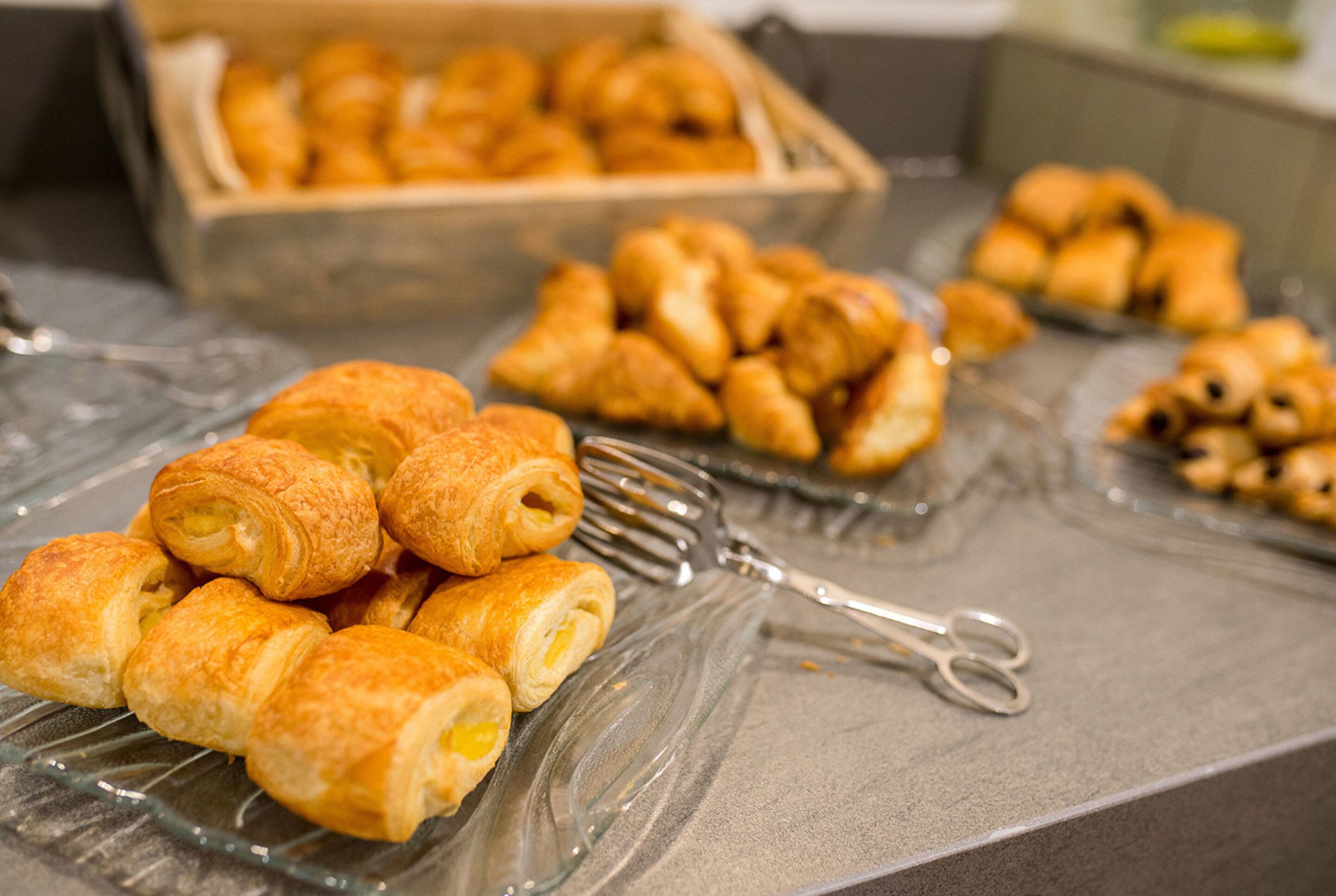 Noutopöytä, jossa on tarjolla erilaisia leivonnaisia, kuten croissantteja ja muita uunissa paistettuja herkkuja.