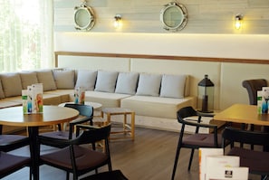 A modern lounge area with a sofa, chairs, and tables. - Hotel Alga (Palafrugell)