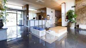 Un vestíbulo moderno con mostrador de recepción, zona de estar y escalera que conduce a plantas superiores.