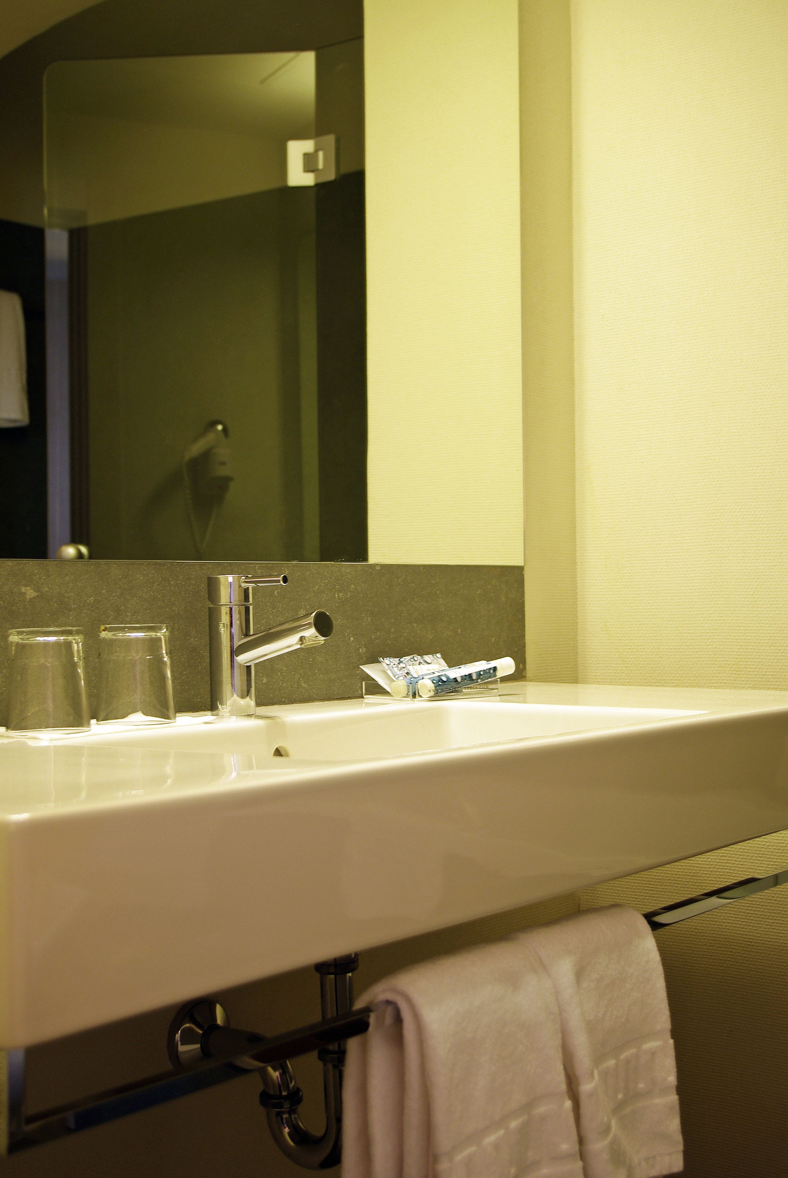 Une salle de bain d’hôtel avec un lavabo, un miroir et un porte-serviettes.