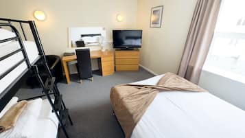 A hotel room with a bed, a desk with a chair, a television, and a bunk bed.