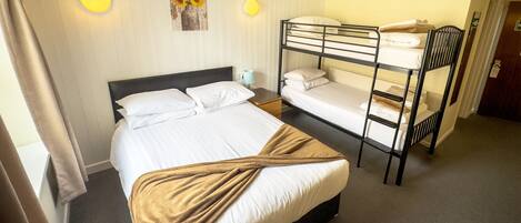 A hotel room with a single bed, a bunk bed, and a wall-mounted light fixture.